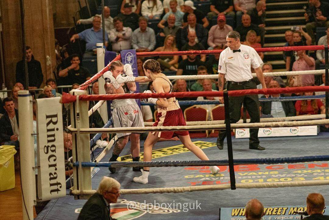 Emma Dolan punching her opponent in the face, as the opponent is up against the ropes.