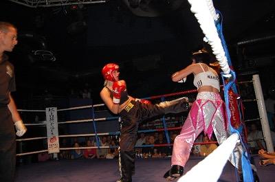 Action shot of Louise Orton kicking her opponent in a kickboxing fight.